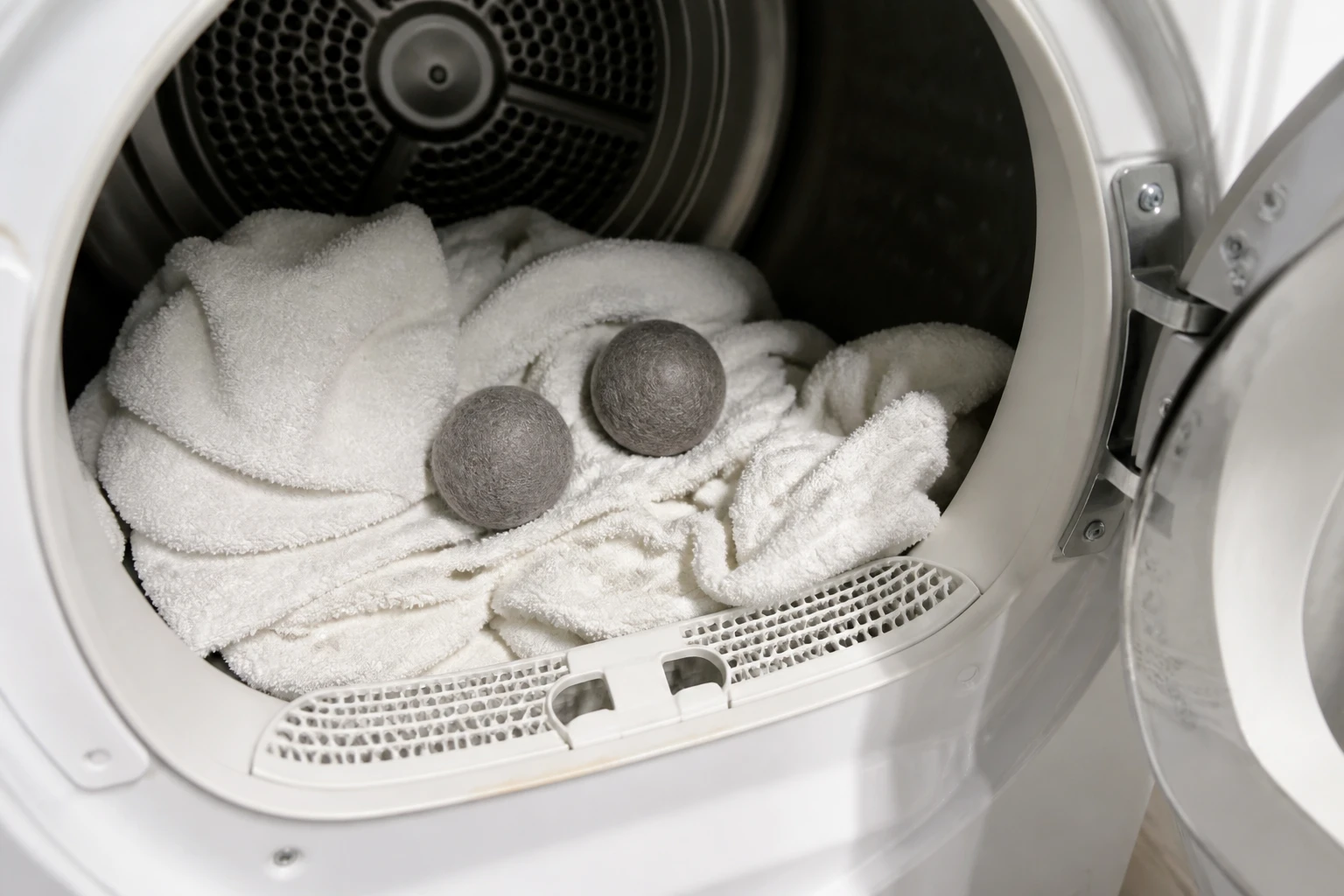 Boules de laine posées sur du linge dans un tambour de sèche-linge ouvert