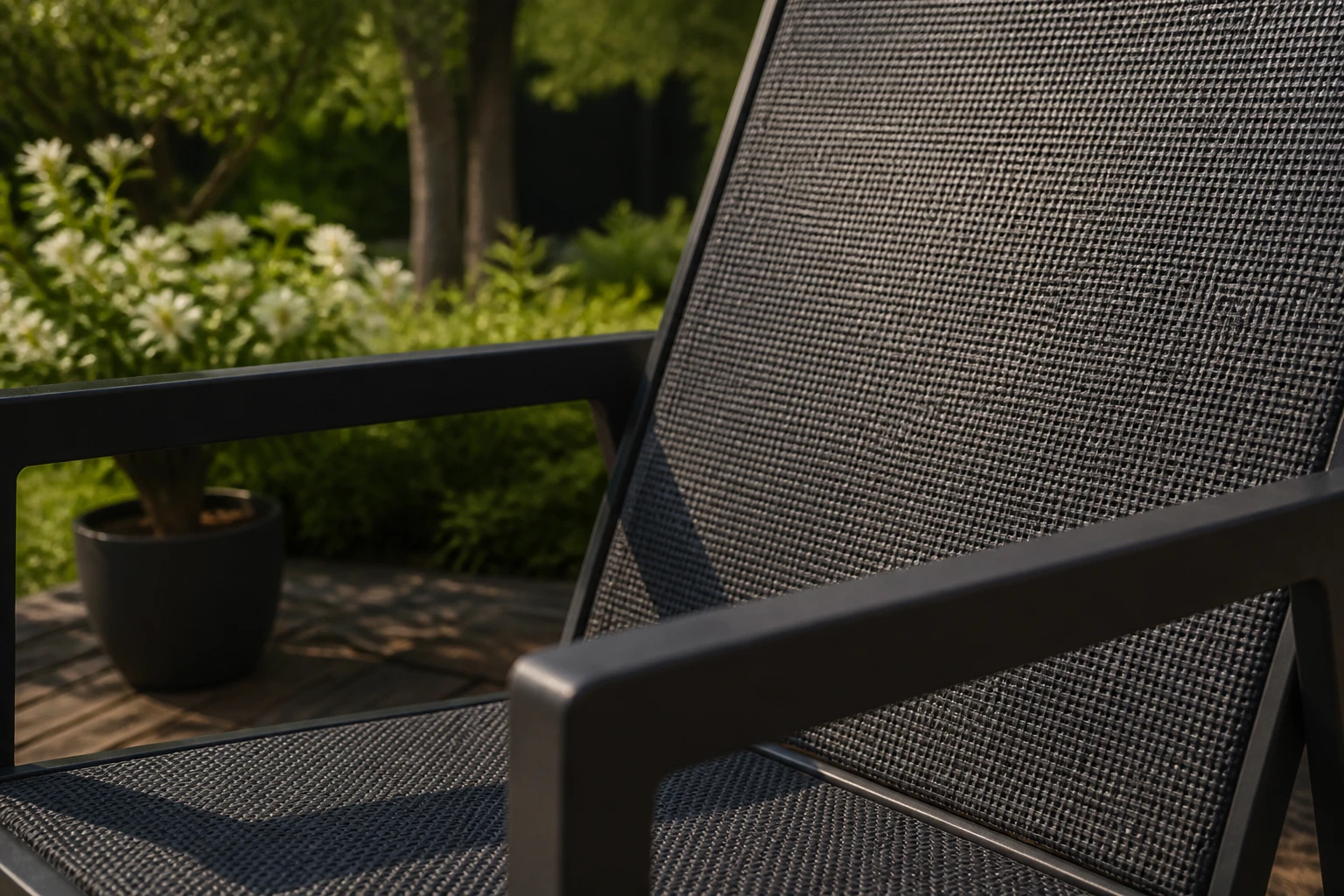 Fauteuil de jardin en textilène gris posé sur une terrasse en bois ensoleillée